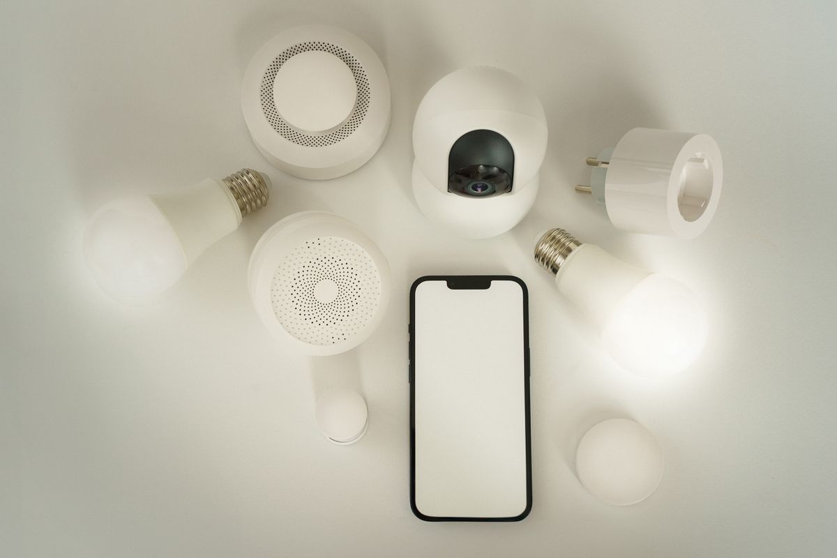 Smart bulbs, a smart plug, a sensor, and a phone arranged on a table