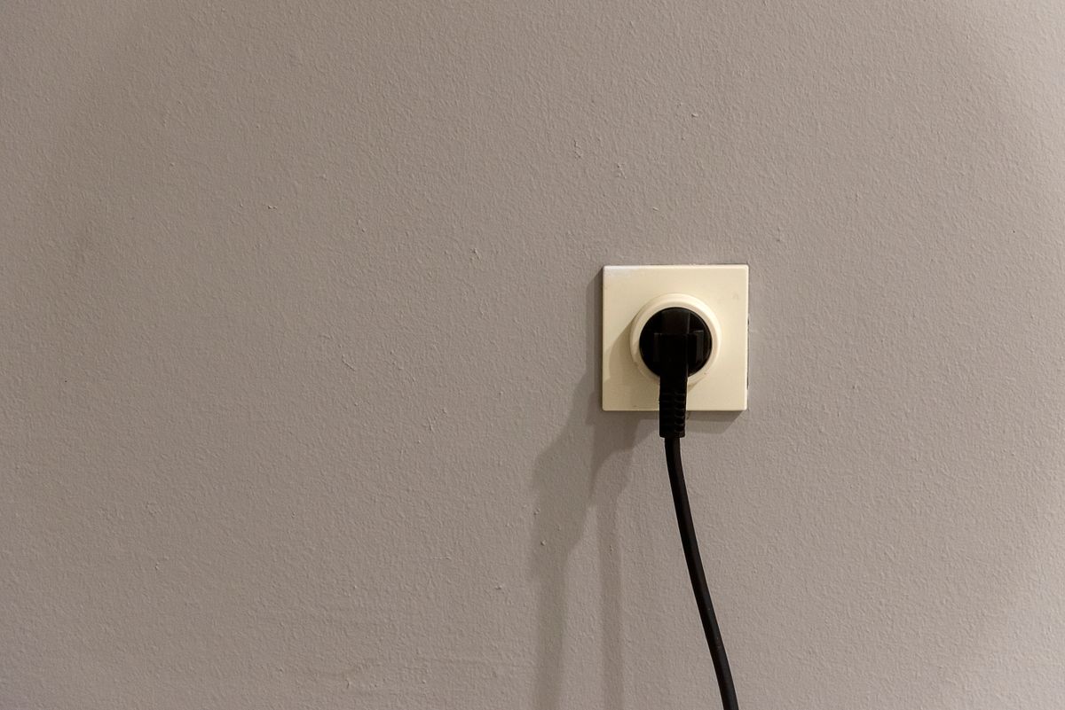 A plug inserted into a plain wall power outlet