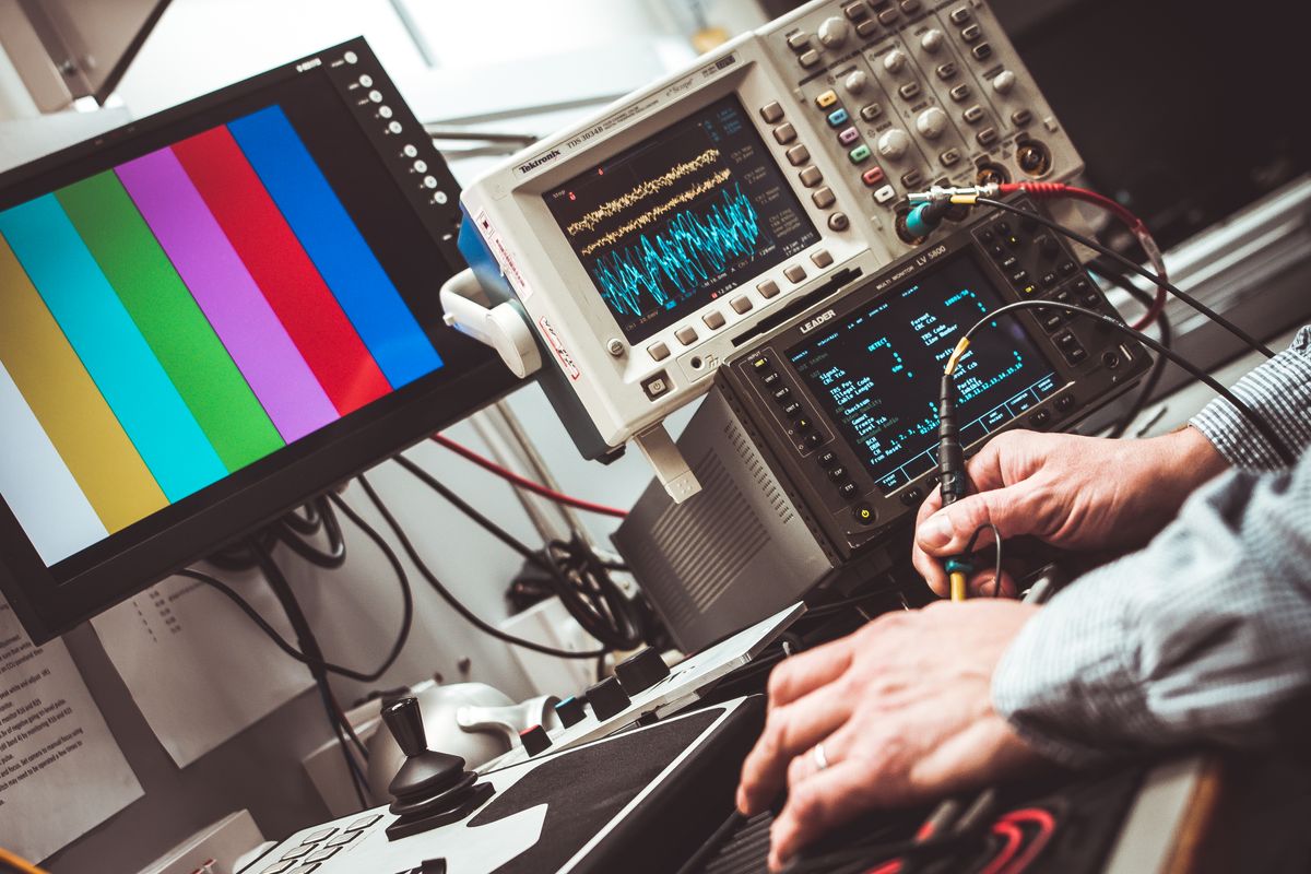 Hands working an oscilloscope and signal analyser on a connected product test bench
